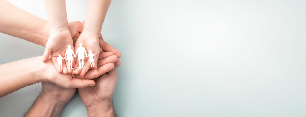 Family care concept. Hands with paper silhouette on table.