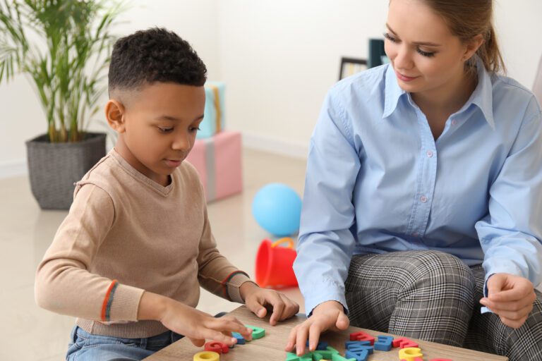 Little boy with speech therapist composing words of letters in office